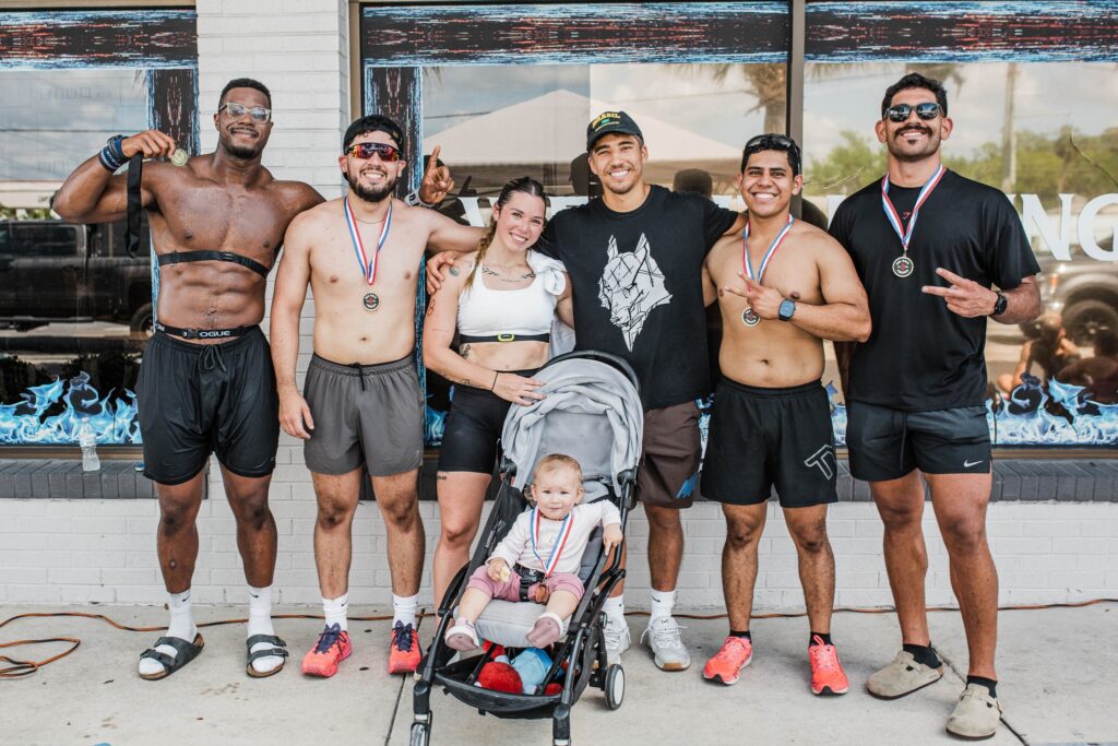 Group of six athletes wearing medals pose for a photo after the Rox Race at Iron Legion Strength and Combat